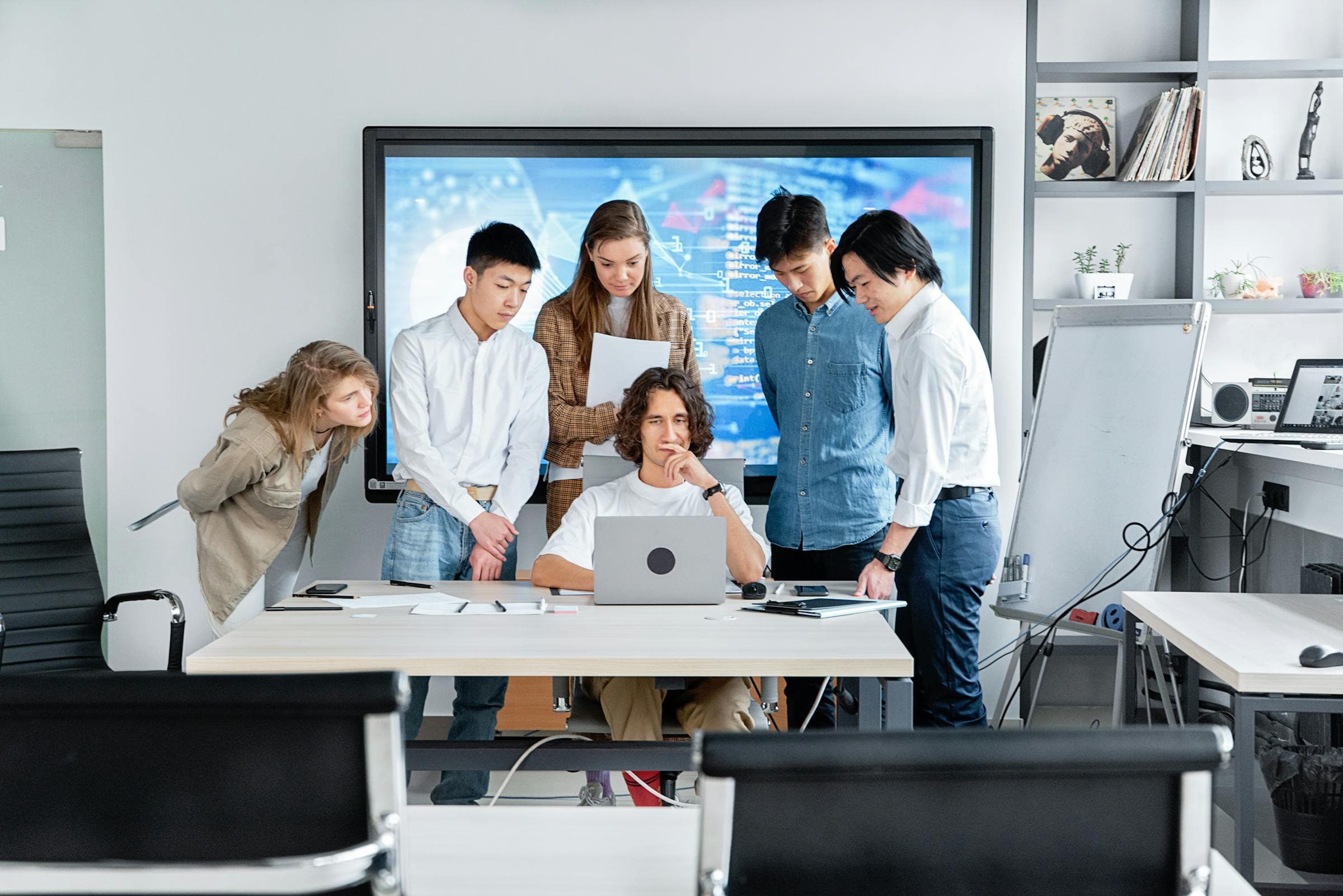 A technology team collaborating around a laptop in a modern office