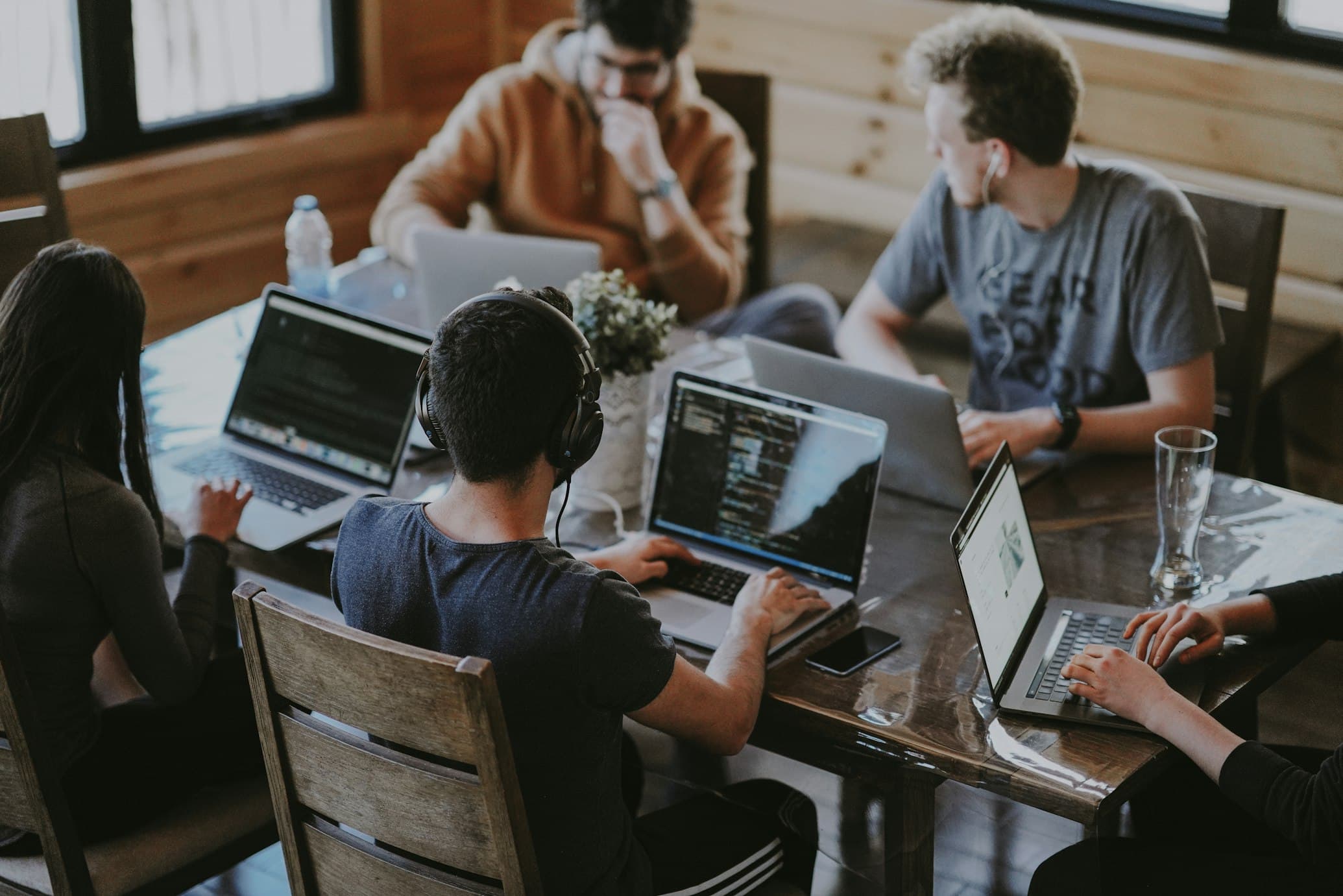 A team of technology professionals collaborating around laptops